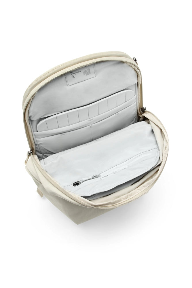 An open beige backpack showing its light gray interior compartments, including a padded insert and zippered pocket, on a white background.