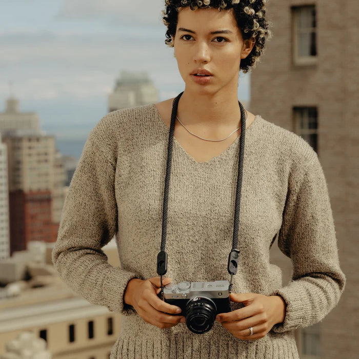 Person holding a camera on a rooftop with cityscape in the background