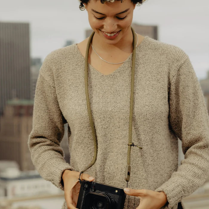 Woman holding a camera with a blurred cityscape background