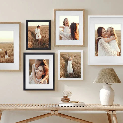 Wall with framed photographs and a lamp on a wooden console table.