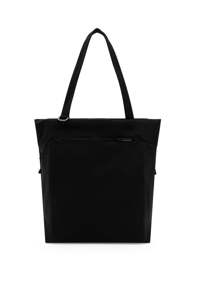 A black canvas tote bag with two shoulder straps and a front zippered pocket, shown against a plain white background.