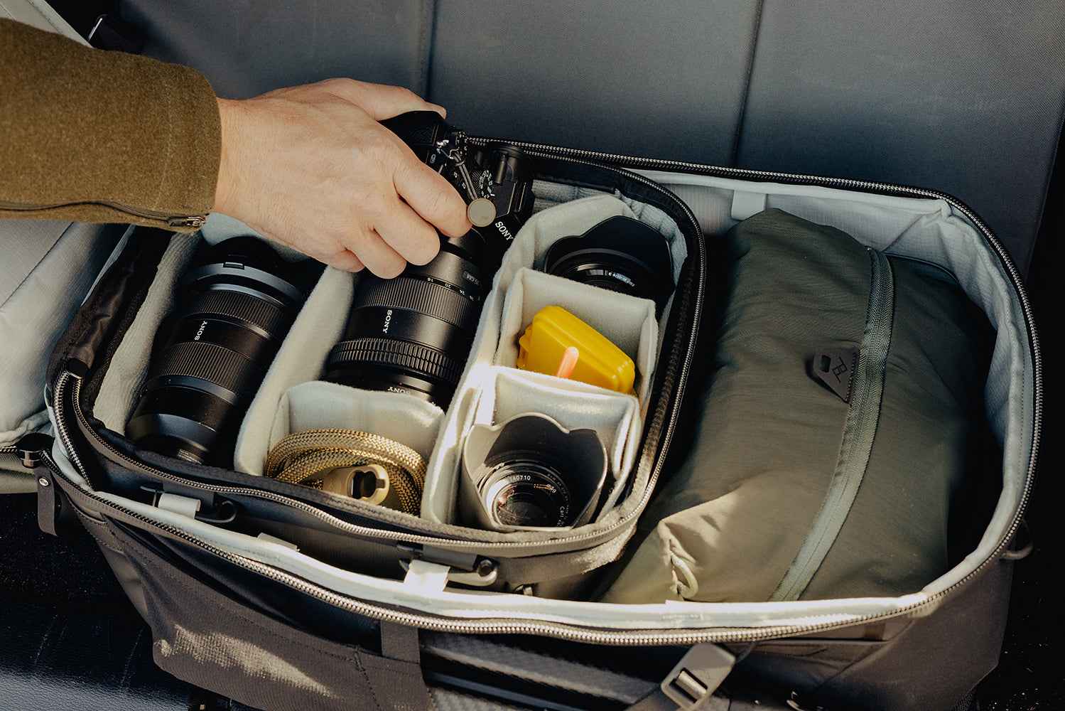 Camera equipment in a travel bag with a hand reaching in
