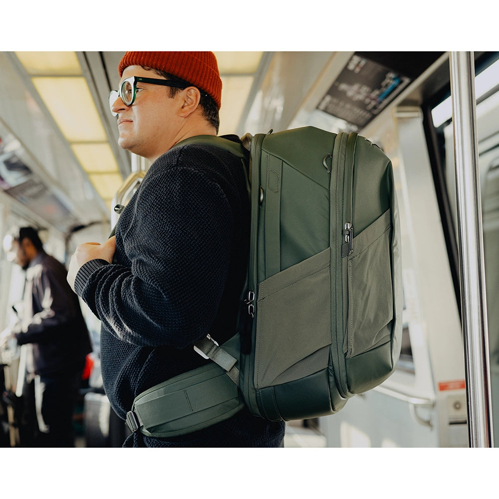 Man wearing a green large backpack on a bus