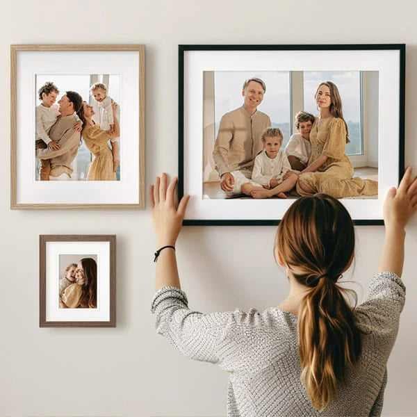 Woman arranging framed family photos on a wall