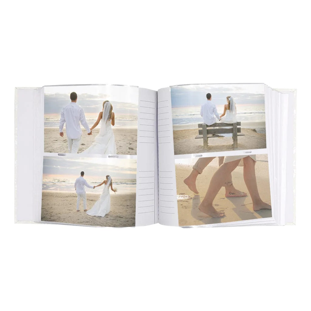 An open white photo album showing printed wedding photographs of a couple on a beach, photographed against a plain white background.